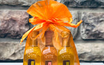 Two bottles of balsamic wrapped in orange paper with a bow against a stone wall background